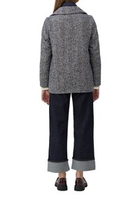 Texturiertes Blazer in Marineblau und Weiß mit Fischgrätenmuster und großen Revers. Kombiniert mit weiten, dunklen Denim-Hosen, umgeschlagenen Säumen und Brogues.