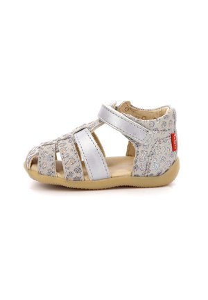 Sandal de cuero plateado con punta abierta, correas entrelazadas, parte superior texturizada y suela de goma de color marrón claro. Correa ajustable con cierre de gancho y bucle.