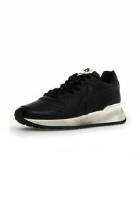 Scarpa sportiva nera con tomaia in pelle, dettagli in rilievo, suola intermedia bianca spessa e suola esterna in gomma strutturata. I lacci sono neri.