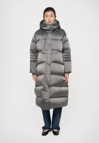 Grijze pufferjas met hoge kraag, horizontale stiksels en een ontwerp van volledige lengte. Gemaakt van glanzend materiaal, met een ritssluiting.