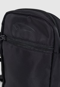 Zwarte nylon rugzak met een gladde textuur, voorzien van een voorvak met ritssluiting en een subtiel logo-embleem. Compact ontwerp voor veelzijdig gebruik.