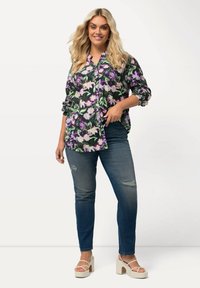 Kukkakuvioinen nappilistapaita, jossa on purppuran ja vihreän sävyjä mustalla taustalla, yhdistettynä kuluneisiin sinisiin farkkuihin ja korkokenkiin.