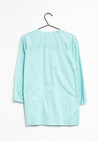 Camicetta azzurro chiaro a maniche lunghe con scollatura rotonda, dettaglio arricciato sul retro e polsini con bottoni, realizzata in un tessuto morbido e liscio.