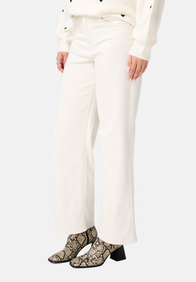 Witte wijde jeans van een gladde stof, gecombineerd met zwart en beige slangenprint enkellaarsjes met een chunky hak.