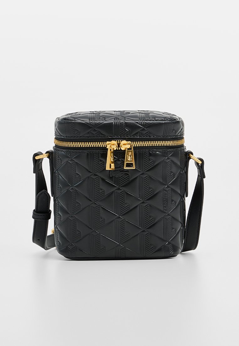Sac en cuir texturé noir avec des motifs géométriques, détails de fermeture éclair dorés et bandoulière ajustable. Forme compacte et cylindrique avec une base solide.