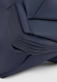 Borsa blu navy con texture plissettata unica, realizzata in materiale sintetico liscio, con elementi di design angolari su un lato.