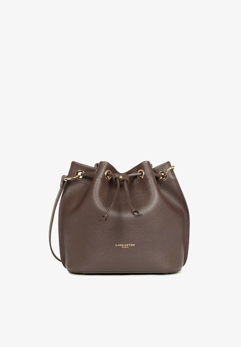 Sac seau en cuir marron avec fermeture à cordon, œillets dorés, fine bandoulière et logo doré "Lancaster Paris" sur le devant.
