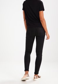 Svarta skinny jeans med hög midja, femfickorsdesign och subtil stretch. Kombinerat med glittriga sneakers i roséguld.