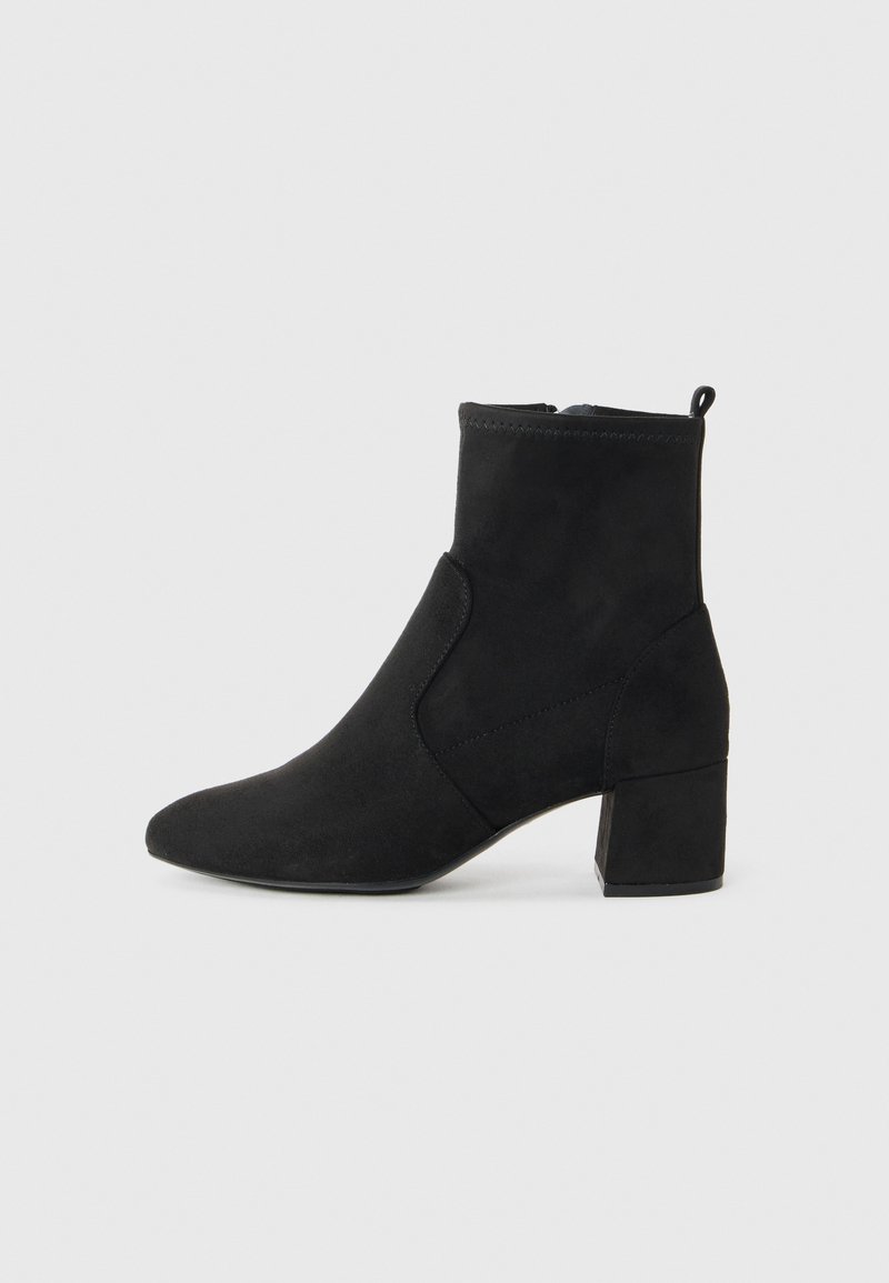 Stivaletto in suede nero con tacco a blocco, punta tonda, cerniera laterale e piccolo strap sullo sfondo bianco uniforme.