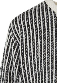 Pull en tricot avec des rayures verticales noires et blanches. Tissu texturé avec un col côtelé et une coupe ample.
