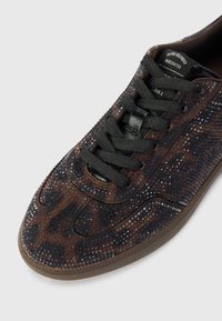 Sneaker marrone e nero con un design testurizzato a macchie di leopardo, lacci neri e suola in gomma. Realizzato in suede e materiali sintetici.