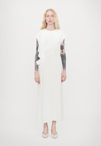 Weißes, knielanges Kleid mit drapierter Detail auf der Vorderseite und kurzen Ärmeln. Glattes Material und gerade Silhouette. Getragen mit hellen Schuhen.