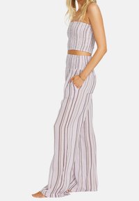 Góra na ramiączkach typu bandeau, krótka, w pionowe paski, zestawiona ze spodnimi o szerokich nogawkach z kieszeniami i elastycznym pasem, w jasnych kolorach.