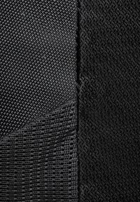 Texturerad svart tyg med två distinkta mönster, ett med ett rutmönster och det andra med en subtil geometrisk design.