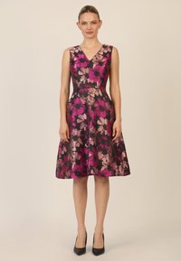 Ein knielanges, ärmelloses Kleid mit tiefem V-Ausschnitt und schwarzem Hintergrund, der mit großen rosa und mauvefarbenen Blumenmustern verziert ist.
