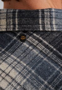 Ruudullinen villapaita tummansinisenä ja off-white-värisenä, jossa on teksturoitu pinta. Kauluksessa on musta PME Legend -logo.