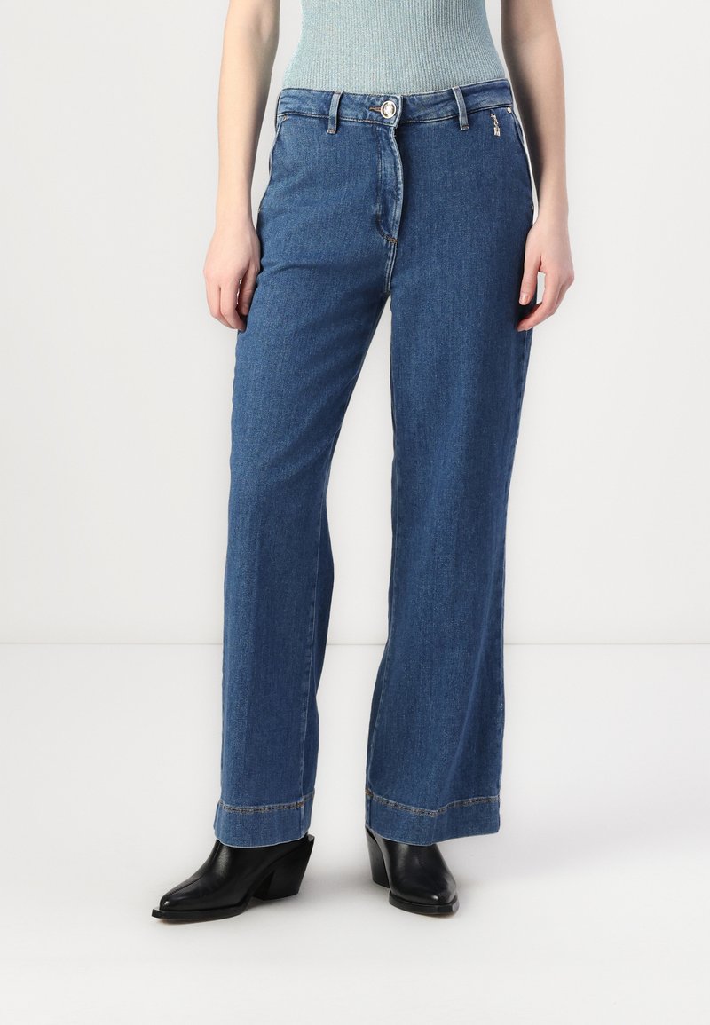Široke denim jeans v srednje modrem pranju, z zadrgo in gumbom za zapiranje, sprednjimi žepi in čistim, obrobljenim robom.