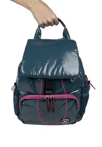 Mochila de color teal brillante con dos bolsillos con cremallera, un asa en la parte superior, bolsillos laterales de malla y acentos rosas en el cierre y los detalles.