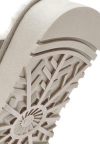 Lichtbeige schoenzool met een gestructureerd patroon van geometrische vormen en een cirkelontwerp in het midden, dat grip en stabiliteit biedt.