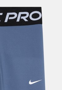 Shorts Nike Pro de couleur bleu clair, avec une taille noire portant l'inscription "PRO" en lettres blanches et un logo Nike swoosh blanc sur la jambe.
