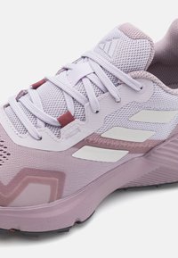 Helllila Adidas Laufschuh mit weißen Streifen, Mesh-Obermaterial und Schnürverschluss, seitlich und von oben gezeigt.