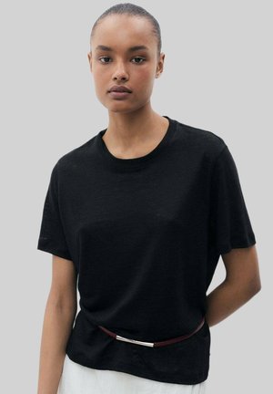 Black short-sleeve t-shirt made of soft fabric, featuring a round neckline and slight drape, worn with a slim maroon belt.