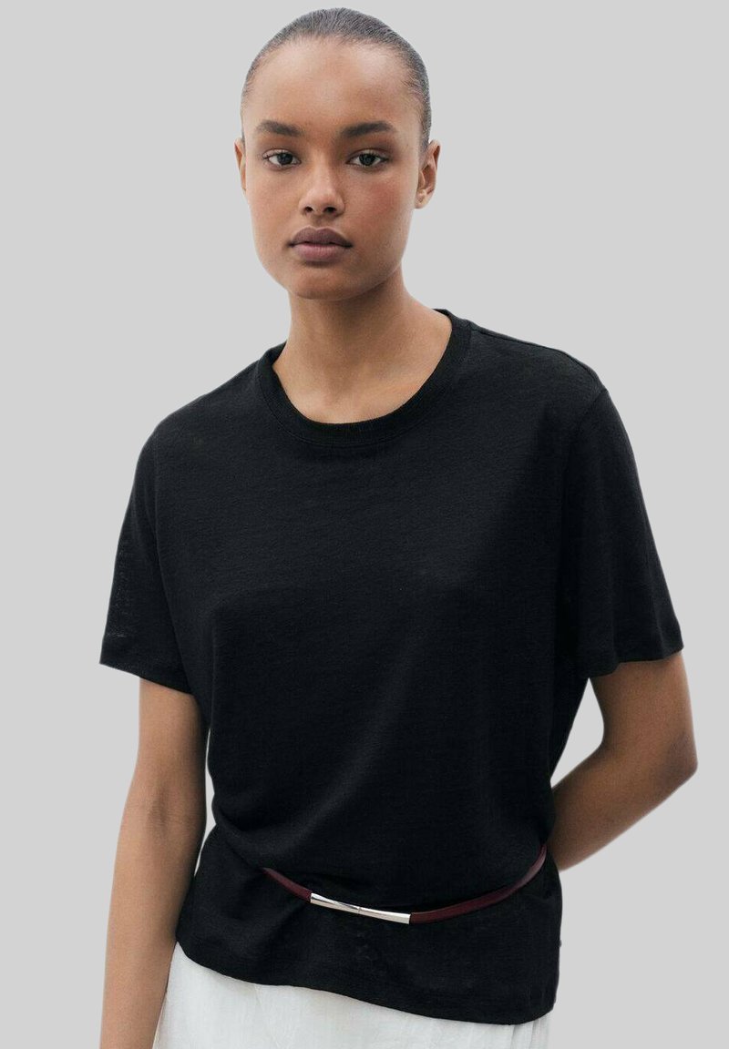 Czarny t-shirt z krótkim rękawem, wykonany z miękkiego materiału, z okrągłym dekoltem i delikatnym zwisem, noszony z wąskim bordowym paskiem.