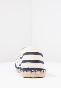 Leinenslipper mit Rückansicht, ausgestattet mit einem weiß-blauen Streifendesign, Jutesohle und geflochtenem Rand. Glatte Textur, abgerundete Form.