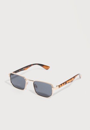 Arany színű fémkeretes, téglalap alakú napszemüveg, sötétszürke lencsékkel és barna teknősmintás szárakkal, világos felületen elhelyezve.