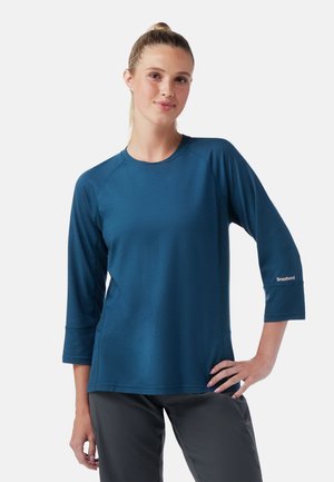 Blauwe, lange mouwen sporttop met raglanmouwen, gemaakt van een lichtgewicht materiaal. Heeft een logo op de manchet en een relaxte pasvorm.