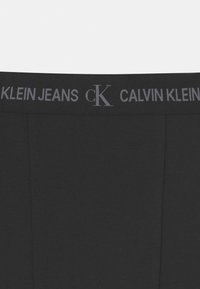 Černé bavlněné brazilky s měkkým elastickým pasem, na kterém je šedě vytištěno "CALVIN KLEIN JEANS" a "cK". Jednoduchý, hladký design.