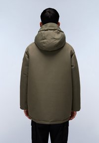 Cappotto imbottito verde oliva con cappuccio, caratterizzato da una texture liscia e un collo rotondo. La vista posteriore mostra maniche completamente coperte e orlo.