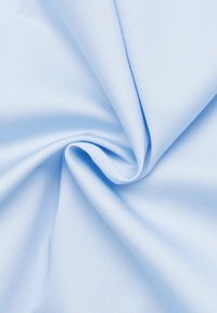 Tessuto blu chiaro che mostra una texture liscia, con una leggera lucentezza. Il materiale è raccolto, mettendo in risalto il suo fluire e la sua caduta.
