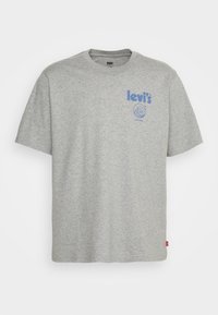 T-shirt gris Levi's à manches courtes avec un logo bleu et un motif en forme de vague sur la partie supérieure gauche de la poitrine.