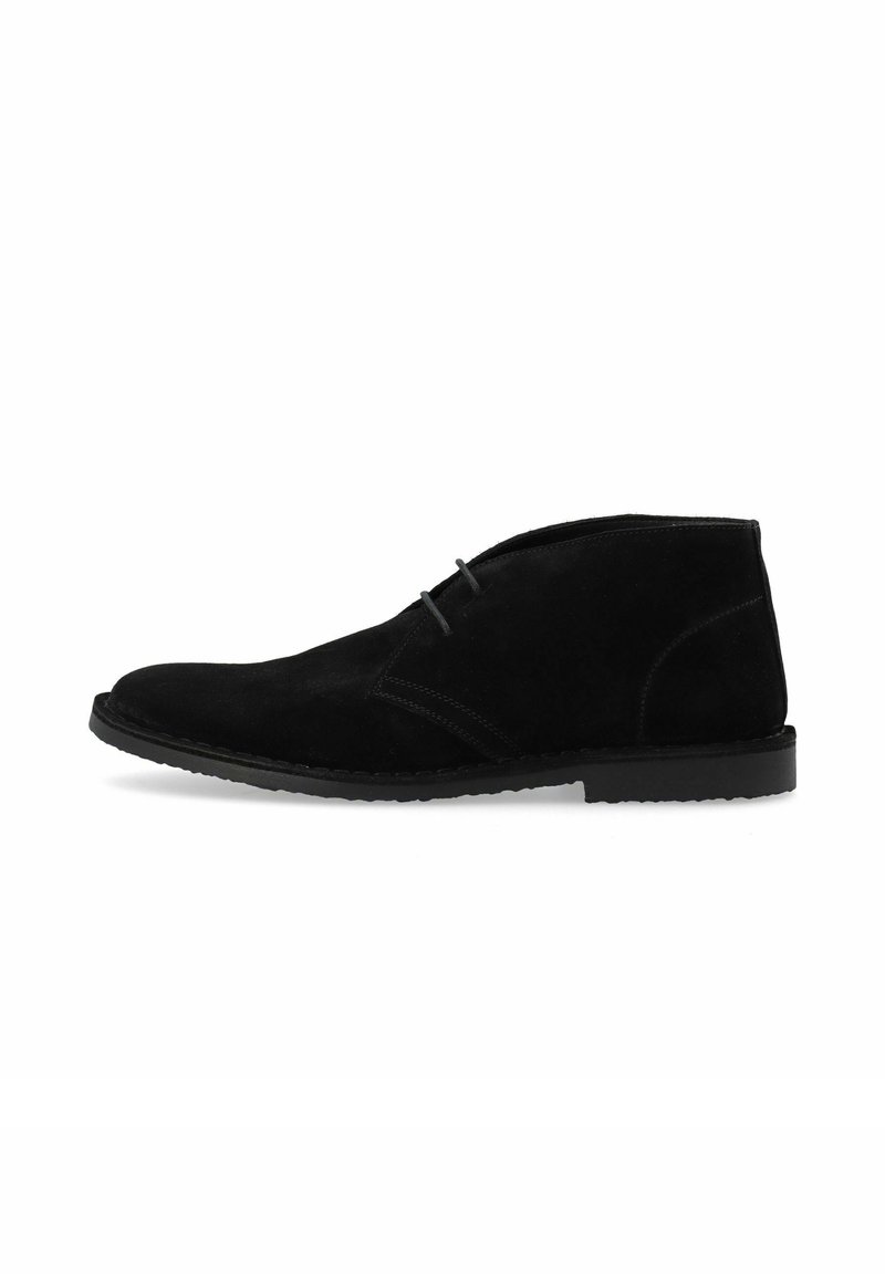 Bottines en suède noir avec un bout arrondi, un minimum de couture et une semelle en caoutchouc plate. Le design est simple et classique.