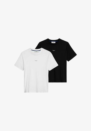 Mann trägt ein schwarzes Marc O'Polo Denim T-Shirt mit kurzen Ärmeln und hellblauen Jeans, eine Hand in der Tasche, beschnitten am Hals und an den Hüften.