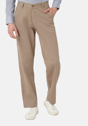 Pantalones de algodón beige con un diseño de pierna recta, que cuentan con un cierre de botón y bolsillos frontales, combinados con zapatillas blancas.