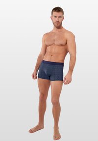 Námořnické modré boxerky s geometrickými vzory, vyrobené z elastického materiálu, s kontrastním pasem a přiléhavým střihem.