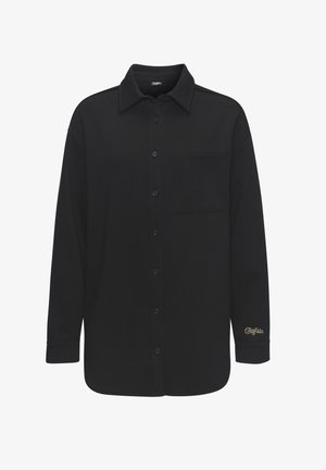 Schwarze langärmlige Hemdbluse aus glattem Stoff mit einer einzelnen Brusttasche und einem goldenen Logo-Akzent am Ärmel.