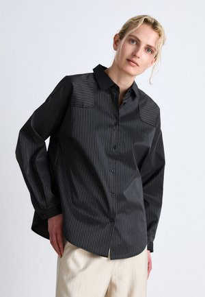 Chemise noire à rayures avec un col, boutons sur le devant et manches longues. Présente des rayures horizontales dans une couleur contrastante et une coupe décontractée.