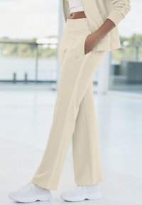 Crème-kleurige sweatpants met een relaxte pasvorm, een elastische tailleband, zijzakken en contrasterende verticale strepen langs de benen.