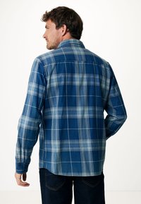Camicia a maniche lunghe con fantasia a quadri blu, dotata di colletto, con tonalità di blu e verde chiaro, realizzata in un tessuto dalla texture liscia.