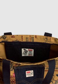 Torba na zakupy z denimu i płótna z żółtym wnętrzem. Posiada wzorzystą zewnętrzną tkaninę, niebieskie akcenty z denimu oraz metki z logo Toy Story.