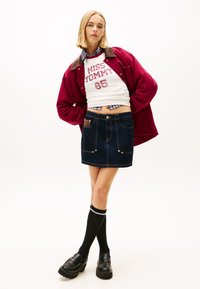 Tumesinise tooniga teksaseelik esitaskutega, kantud koos punase bomberjaka ja valge graafilise lühikese topiga. Mustad põlveni sokid ja platvormkingad.