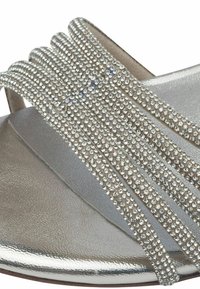 Stříbrné ploché sandály s ozdobným páskem malých skleněných kamínků, lesklou kovovou stélkou a hladkou, strukturovanou podrážkou.