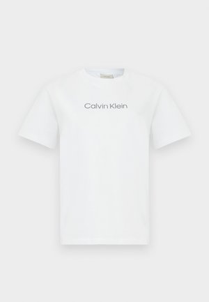 Camiseta de algodón blanca con cuello redondo y mangas cortas. Muestra el texto "Calvin Klein" en gris a lo largo del pecho.