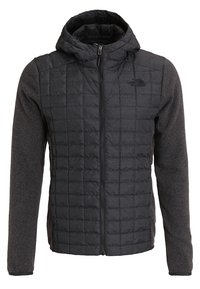 Tummanharmaa, päällystetty etujakku, jossa on huppu, fleece-hihat ja täysi vetoketju. Vasemmassa rinnassa on The North Face -logo.