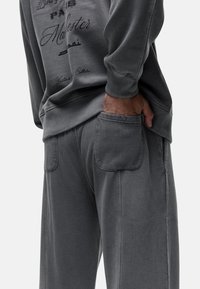 Grijze sweatshirt met tekstdetails op de achterkant en bijpassende grijze joggingbroek, met zijzakken en ribgebreide boorden.