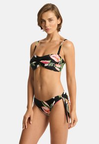 Zwart bikini set met bloemmotieven; de top heeft een geplooid ontwerp aan de voorkant en verstelbare banden, terwijl de onderkant zijstrikjes heeft.