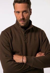 Brauner Fleece-Pullover mit hohem Kragen, Zwei-Knopf-Leiste und dezentem Logo. Verfügt über eine weiche Textur und einen lässigen Schnitt.